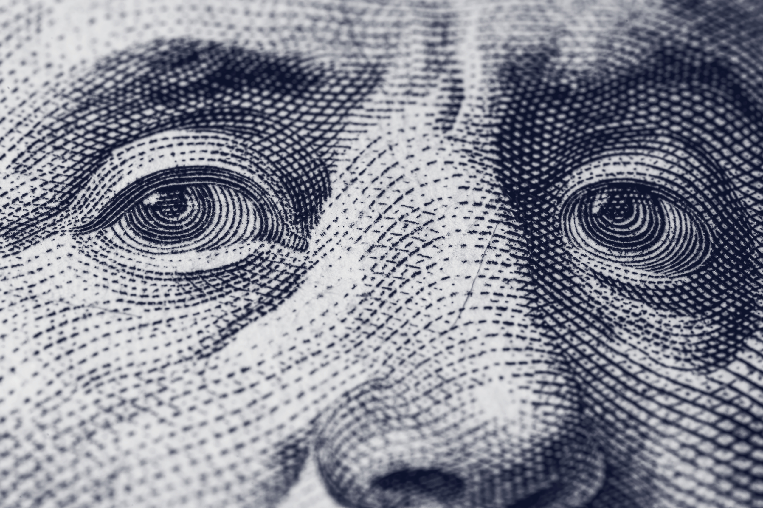 Extreme macro close-up of an engraved portrait on U.S. paper currency, showing the eyes, nose bridge, and the fine cross-hatched line-work used in banknote engraving